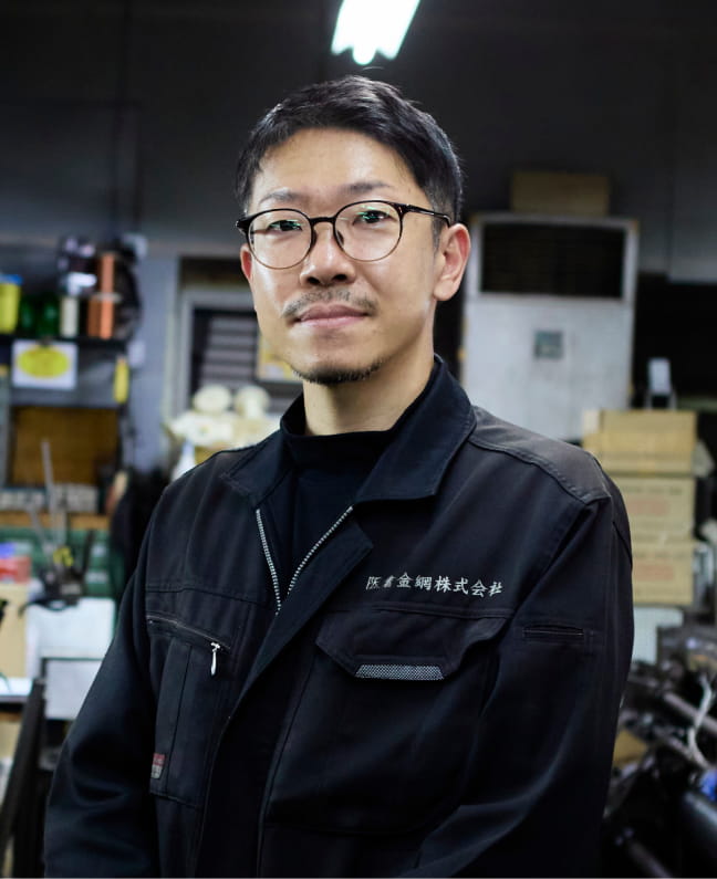 工場内で笑顔を見せる眼鏡の男性社員