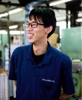 工場内で笑顔を見せる眼鏡の男性社員